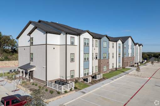 A row of modern townhouses with a red car parked in front.