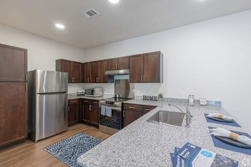 A kitchen with a granite counter top and wooden cabinets.