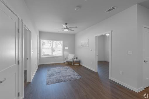 A spacious living room with a rug on the floor and a ceiling fan.