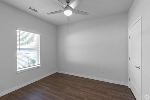 A room with a ceiling fan and a window with blinds.