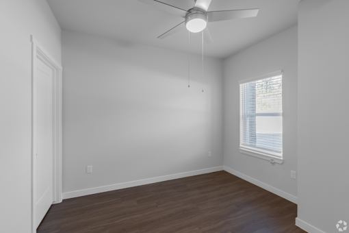 A room with a ceiling fan and a window with blinds.