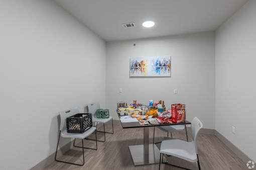 A white room with a table and chairs and a painting on the wall.