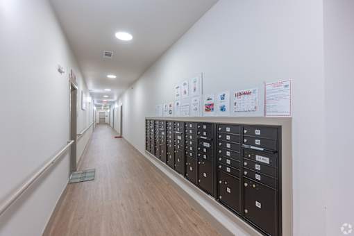 A long hallway with a series of lockers on the right and papers on the wall.
