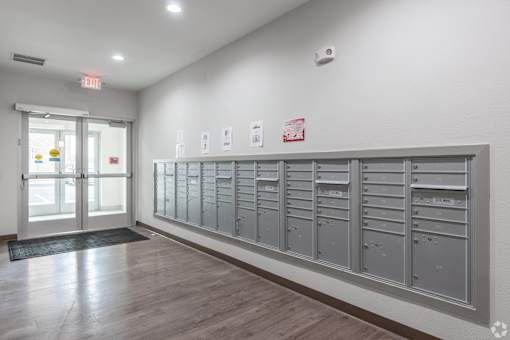A long row of mailboxes are lined up on a wall.
