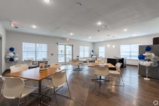 A room with a long table and chairs with balloons on the table.