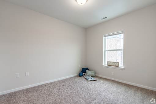 A room with a window and a carpet on the floor.