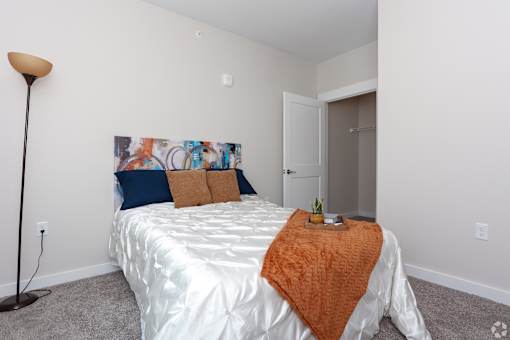 A bedroom with a white bed and a painting on the wall.