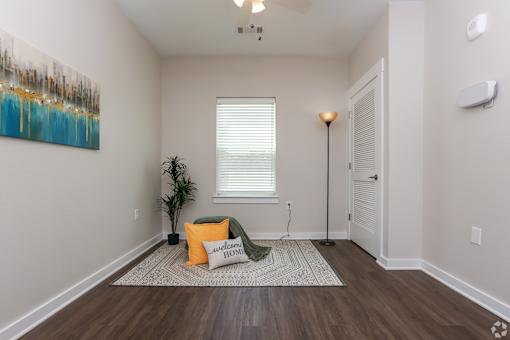 A room with a painting on the wall and a plant on the floor.