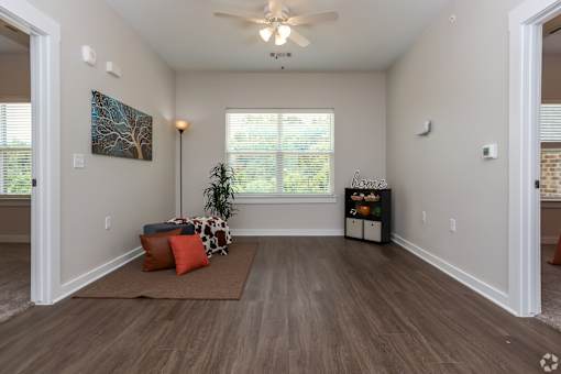 A room with a brown rug and a ceiling fan.