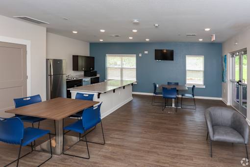 A kitchen with blue walls and a wooden table with blue chairs.