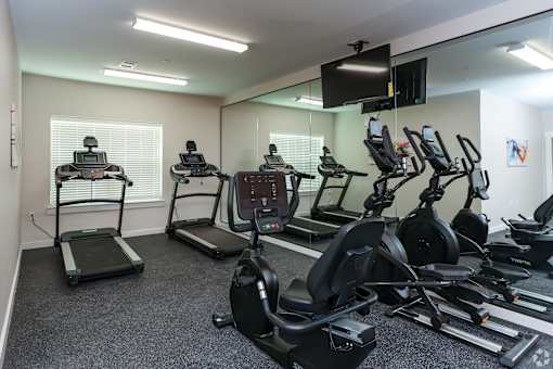 A gym room with treadmills, elliptical machines, and other exercise equipment.