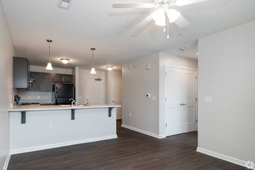 A spacious kitchen and living room with a ceiling fan and lighting fixtures.