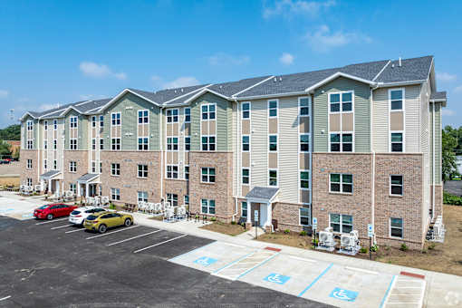 A parking lot in front of a building with cars parked.