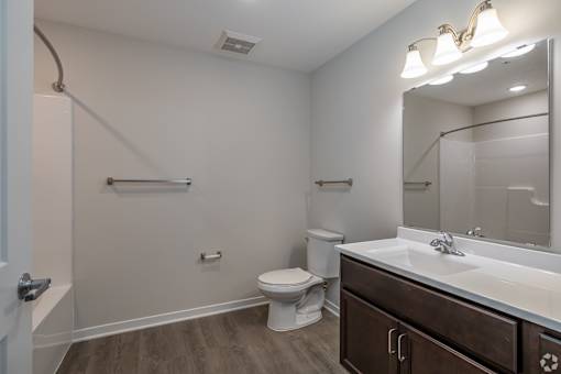 A bathroom with a toilet, sink, and mirror.