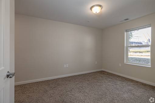 A room with a carpeted floor, a window, and a door.