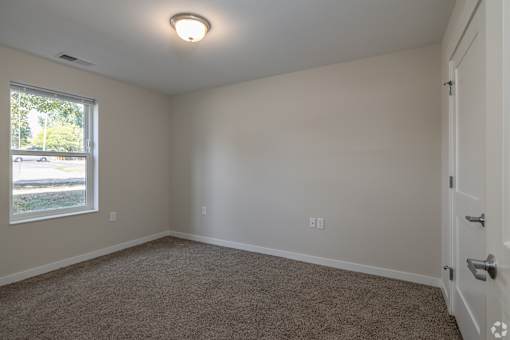 A room with a carpeted floor and a window letting in natural light.