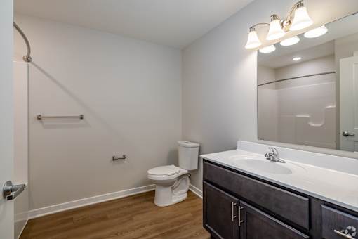 A bathroom with a toilet, sink, and mirror.