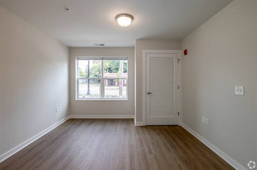 A room with a white door and a window with a view of the street.