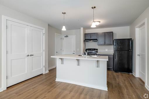 A kitchen with a white island and black fridge.