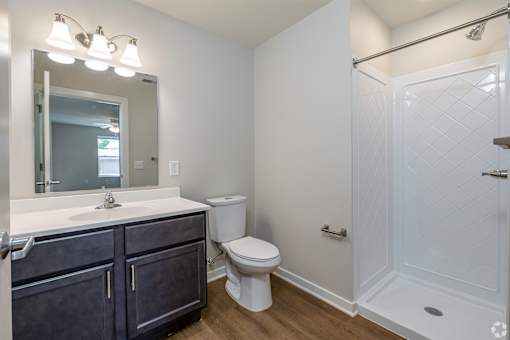 A white bathroom with a toilet, sink, and shower.