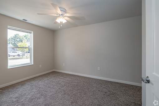 A room with a ceiling fan and carpeted floor.