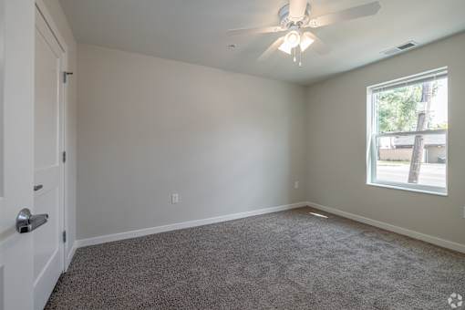 A room with a ceiling fan and carpeted floor.