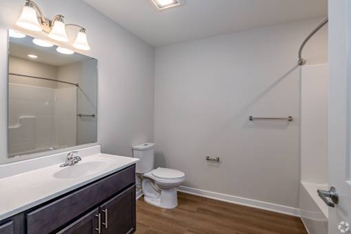 A white bathroom with a toilet, sink, and mirror.