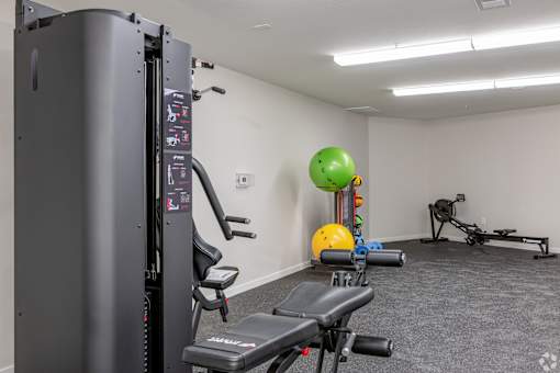 A gym with a treadmill, exercise ball, and weights.