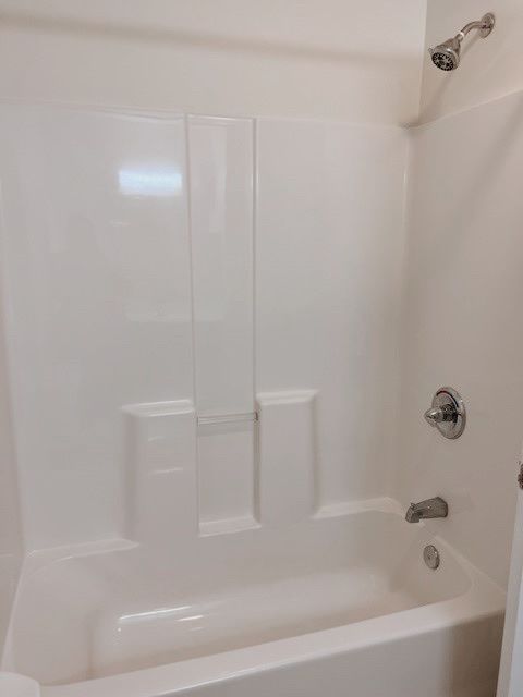 A white bathtub with a shower head and faucet.