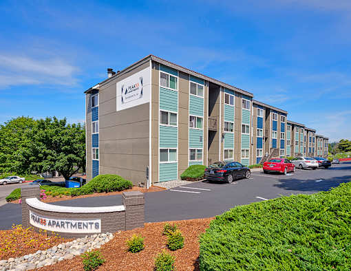 Exterior apartments with green bushes and trees and on-site community parking.