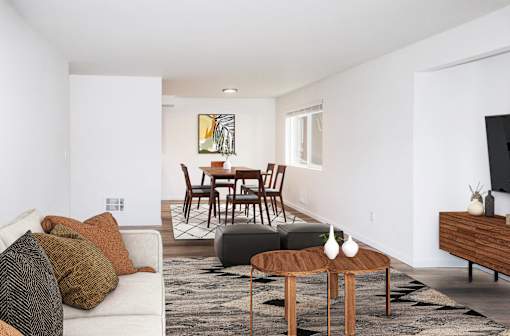 A living room with a white couch, a brown coffee table, and a painting on the wall at our apartments in Renton, WA