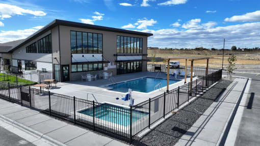 a swimming pool in front of a building with a patio and a poolside building at Yellowstone Landing, Montana