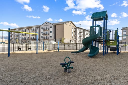 a playground with a slide and swings in front of an apartment building at Yellowstone Landing, Montana, 59714