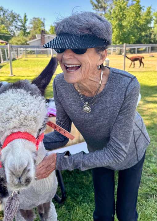 A woman is petting a alpaca at Hearthstone Lodge Senior Residences, California, 95602