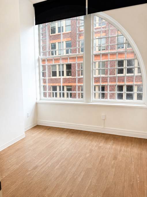 Empty bedroom with arched windows and hardwood floors at Textile Lofts Apartments, Ohio