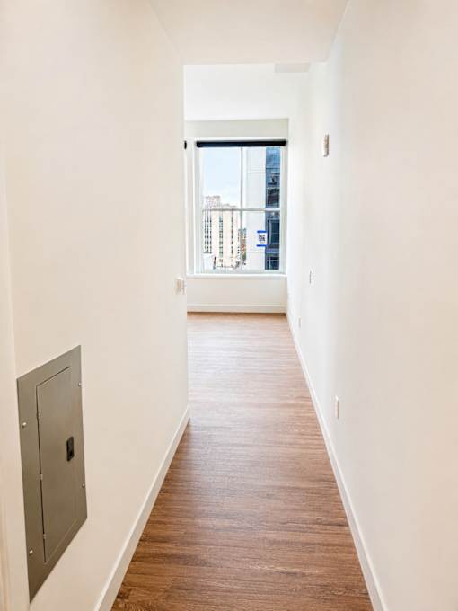 Hallway with hardwood flooring and city view window at Textile Lofts Apartments, Cincinnati, OH 45202