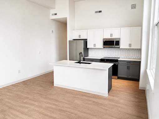 Open kitchen with white island and modern appliances at Textile Lofts Apartments, Cincinnati, 45202