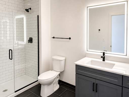 Bathroom with glass shower and white vanity at Textile Lofts Apartments, Cincinnati, OH