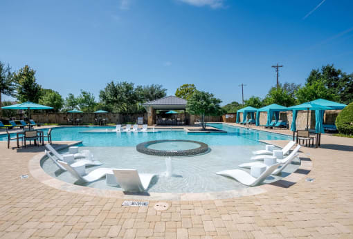 a resort style pool with white chairs and blue umbrellas at Discovery at Craig Ranch, McKinney