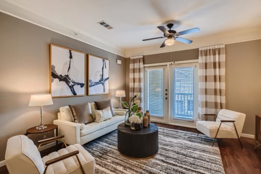 a living room with a couch and a ceiling fan  at Grand Villas Apartments, Texas