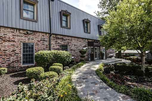 Brick building exterior with landscaped entrance walkway at London House Apartments, Lenexa, KS