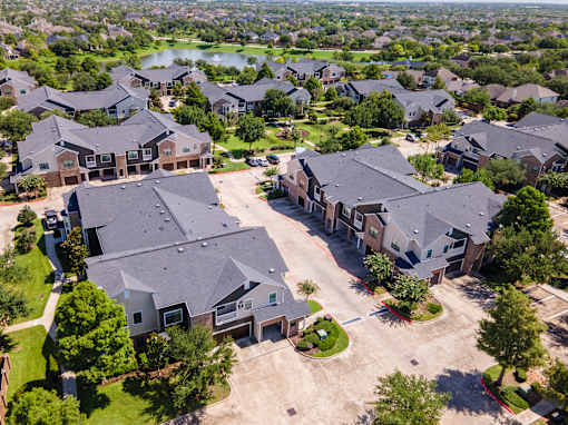 A bird's eye view of a residential area with houses and a lake in the distance at Avenues at Shadow Creek Ranch Apartments, Pearland, Texas
