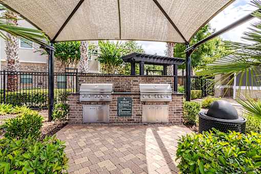 A patio with a grill and a black trash can at Avenues at Shadow Creek Ranch Apartments, Pearland, Texas