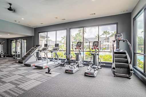 A gym with treadmills, elliptical machines, and a stair climber at Avenues at Shadow Creek Ranch Apartments, Pearland, TX, 77584