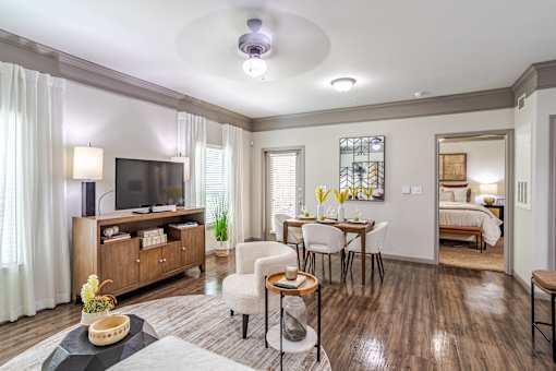 A living room with a television, a dining table, and chairs at Avenues at Shadow Creek Ranch Apartments, Pearland, TX