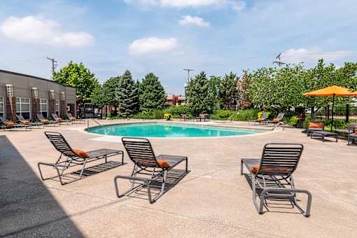 A pool surrounded by chairs and umbrellas with a building in the background. at CityView, North Kansas City, Missouri