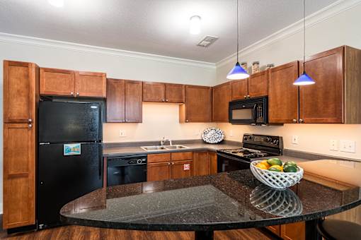 A kitchen with wooden cabinets and a black fridge. at CityView, North Kansas City, Missouri