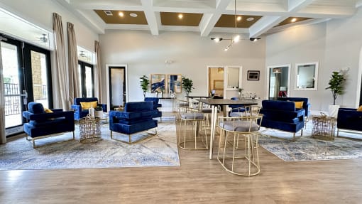 a living room with blue chairs and tables and a kitchen at Waterstone at Cinco Ranch, Katy, TX, 77450