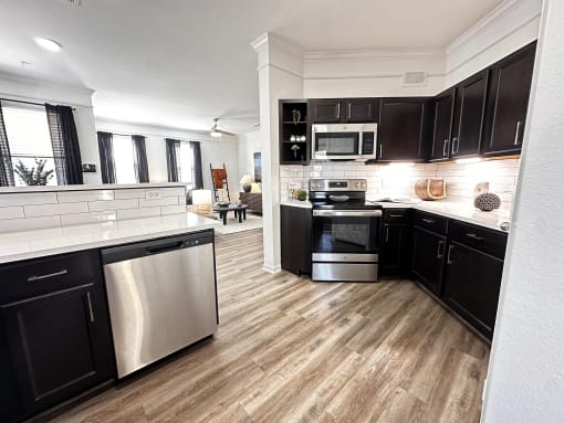a kitchen with black cabinets and stainless steel appliances at Grand Villas Apartments, Katy