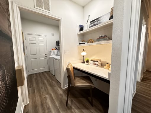 a home office with a desk and a door to a kitchen at Grand Villas Apartments, Katy